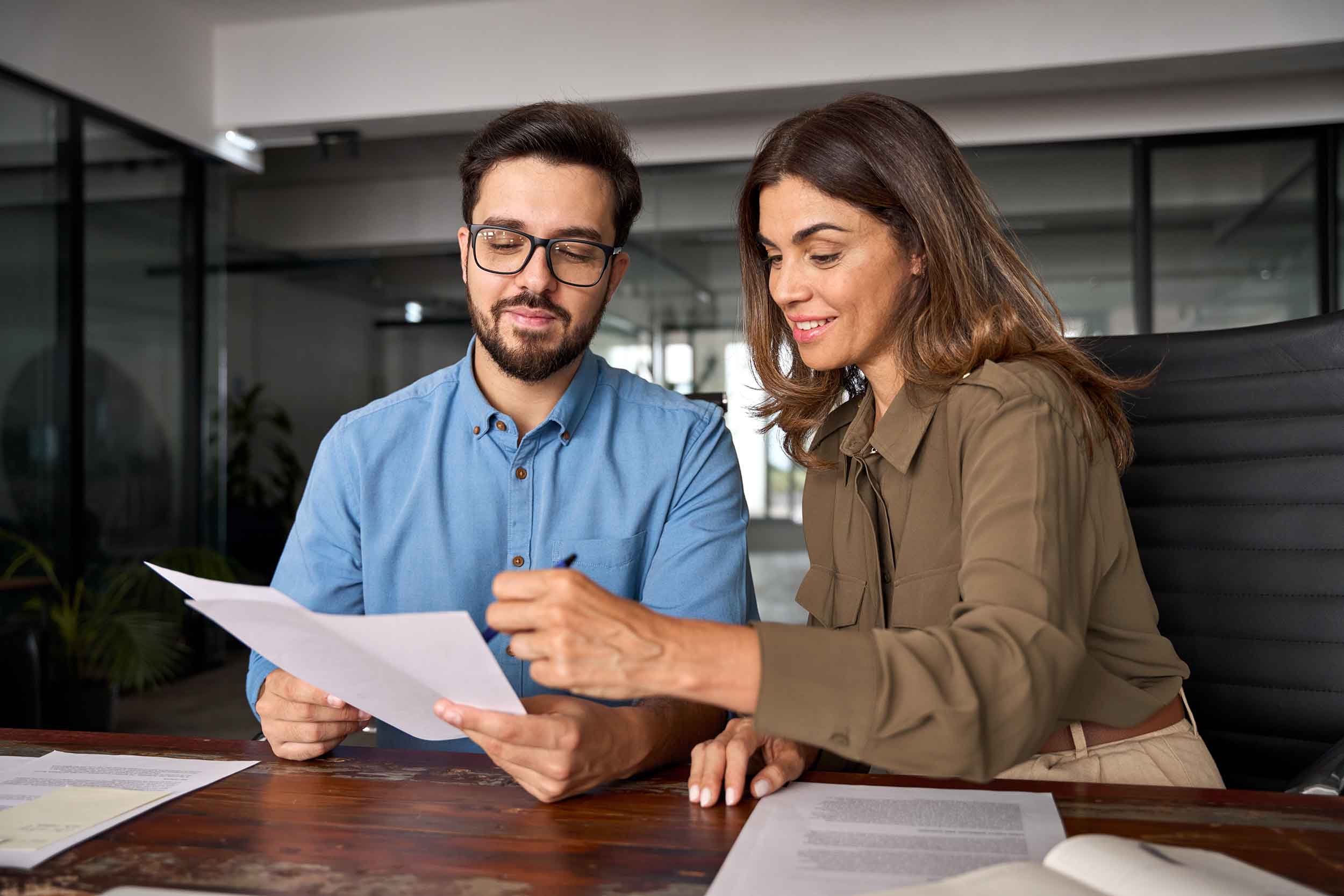 Smiling female financial advisor, consulting client investor reading document at business meeting